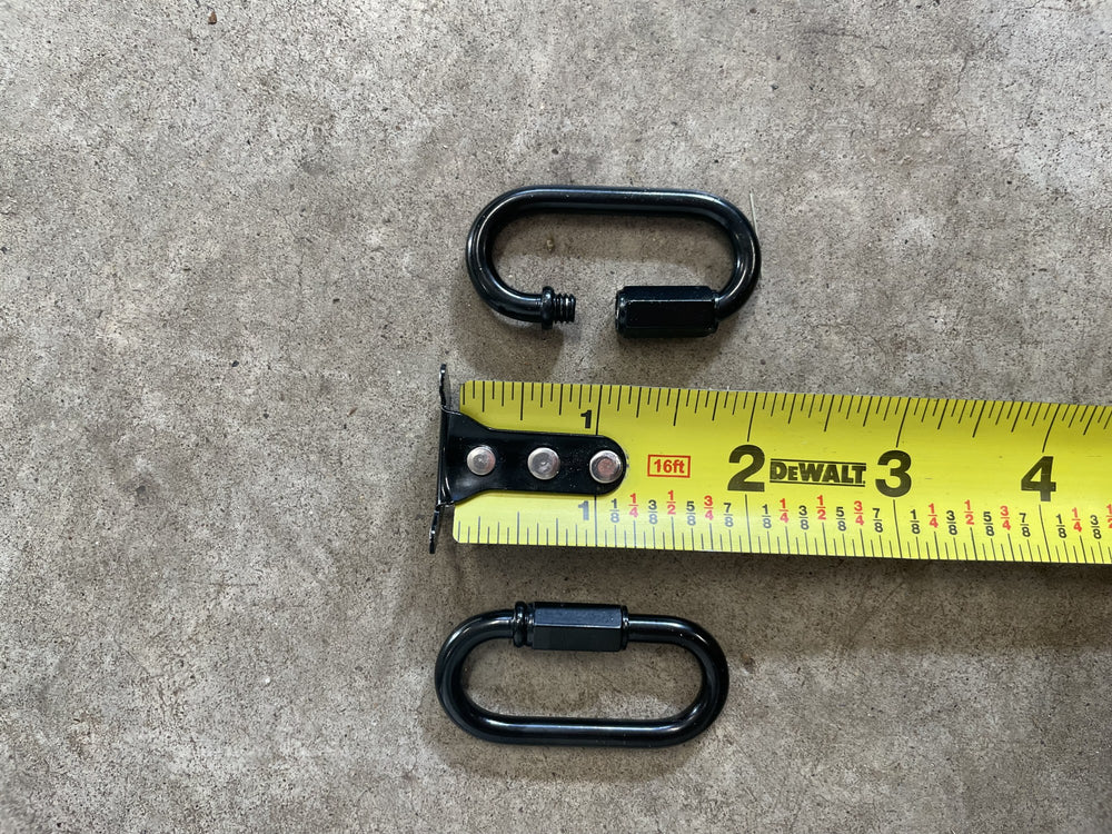 Two black heavy-duty locking carabiners beside a tape measure, one open showing the threaded screw lock